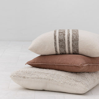 Stack of three textured cushion on a light wooden floor.