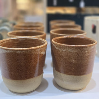 Set of ceramic cups with pink and beige glaze on a white surface.