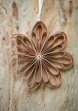 Decorative flower-shaped ornament made of brown paper or fabric on a wooden surface