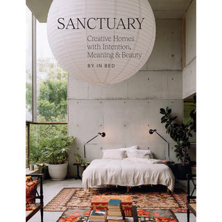 Book cover of 'Sanctuary' with a bedroom scene featuring a bed, plants, and a large pendant light.