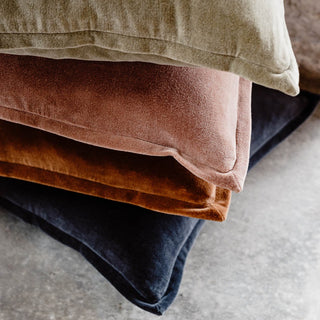 Stack of folded cloths in brown, beige, and blue on a neutral background