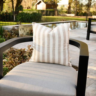 Striped pillow on a chair with a garden and pool in the background