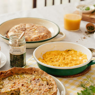 Breakfast table with eggs, bread, and a jar of seasoning on a white tablecloth.