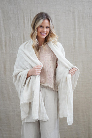 Woman wearing a beige scarf and outfit against a neutral background
