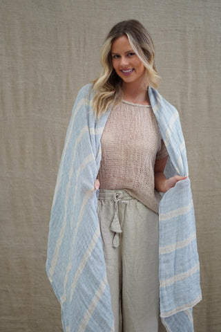 Woman wearing a light blue striped scarf over her shoulders against a beige background