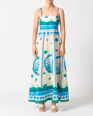 Woman wearing a long dress with blue and green patterns on a white background