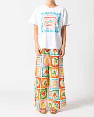 Person wearing a white t-shirt with colorful graphics and a long colorful skirt on a white background