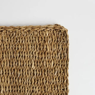 Close-up of a woven seagrass mat on a light gray background