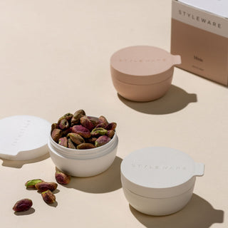 Collapsible silicone food containers with Styleware branding on a beige background