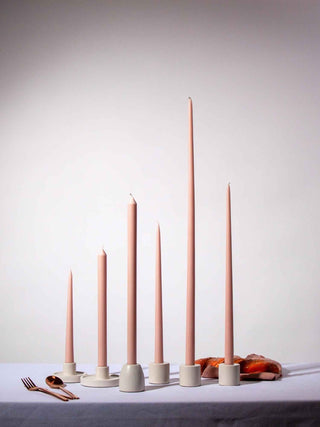 Set of pink candles with white holders on a light gray background