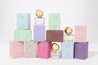 Set of pastel-colored perfume bottles and boxes on a white background