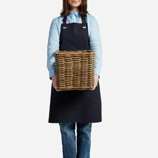 Person wearing a black apron holding a woven basket on a white background
