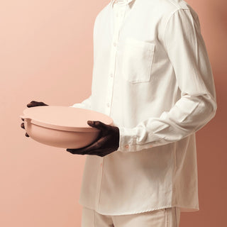 Person holding a pink ceramic bowl against a beige background