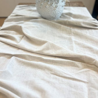 Beige fabric draped over a surface with a textured white object on top.