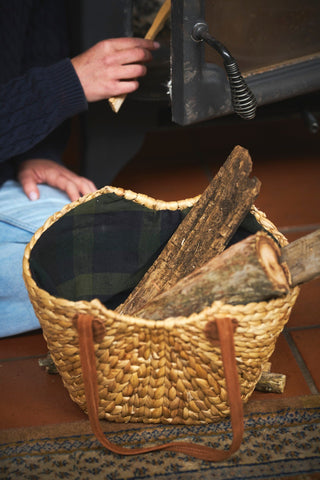 Wicker basket filled with firewood on a wooden floor