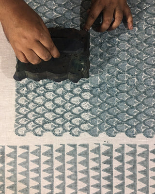 Person using a stamp on a textured fabric surface with geometric patterns.