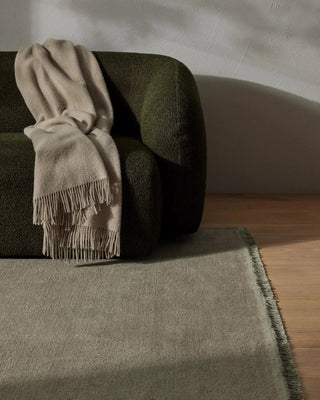 Beige blanket draped over a green armchair on a wooden floor.