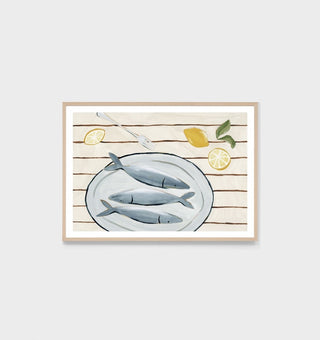Framed artwork of three fish on a plate with lemons on a wooden background.