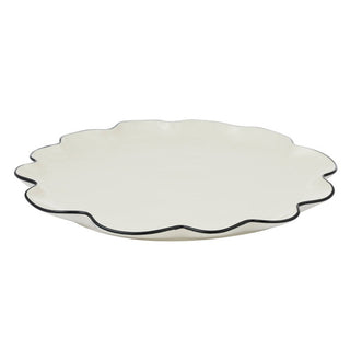 White scalloped-edge plate with black rim on a white background