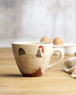 Ceramic mug with a rooster design on a wooden surface
