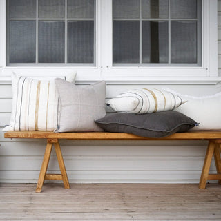 Wooden bench with decorative pillows on a wooden deck.