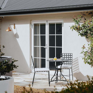 Outdoor patio area with a small table and chairs in front of a house.