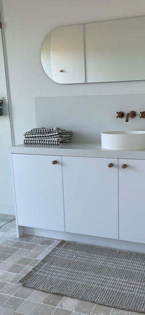 Bathroom with white vanity, mirror, and sink.