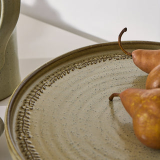 Ceramic plate with decorative edge and pears on a neutral background