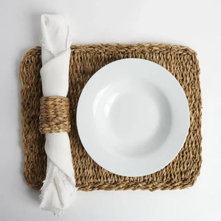 White plate on a woven placemat with a white napkin.