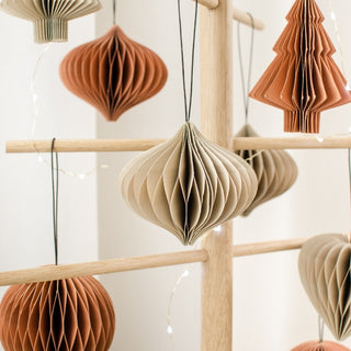 Decorative paper ornaments hanging on a wooden rack against a white background