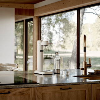 Modern kitchen with a water dispenser, bottle, and faucet in front of large windows.
