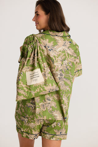 Woman wearing a green floral patterned outfit with a visible brand label on a white background