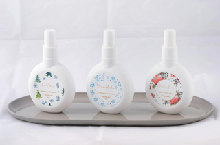 Three white bottles with floral designs on a gray tray against a light gray background