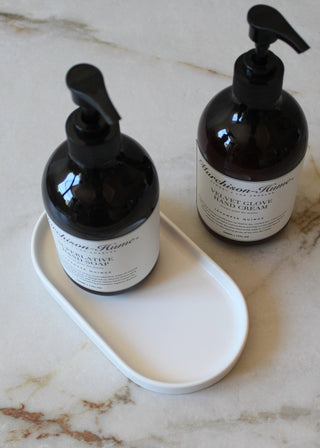 Two black bottles with pump dispensers on a white tray against a marble background