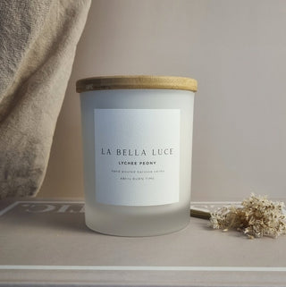 Frosted candle jar with wooden lid and 'La Bella Luce' label on a neutral background