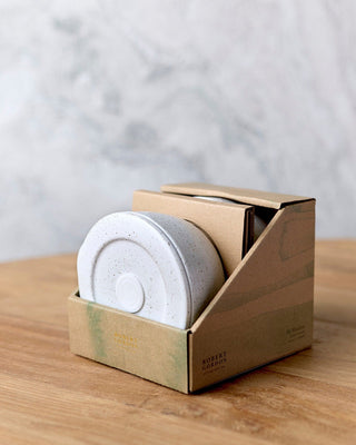 White coffee filter in a cardboard holder on a wooden surface with a light gray background