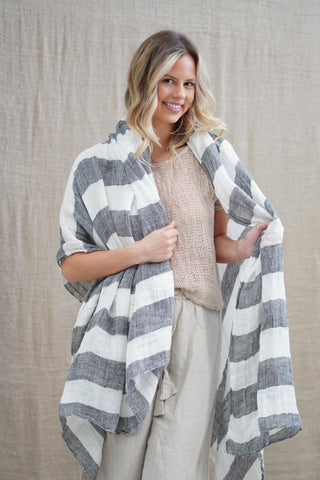 Woman wearing a gray and white checkered shawl against a beige background