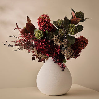 White vase with a bouquet of flowers on a beige background