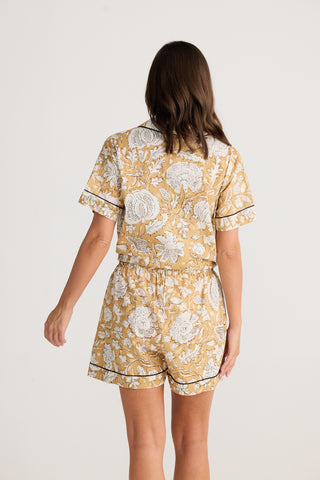 Woman wearing a yellow floral pajama set on a white background