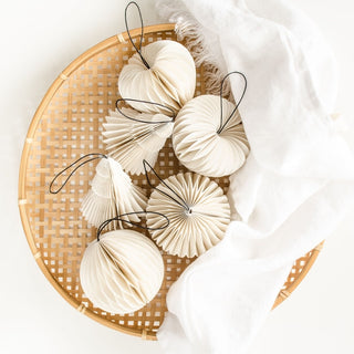 Decorative paper lanterns on a woven basket with a white cloth background