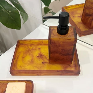 Amber-colored soap dispenser with black pump on a white surface.