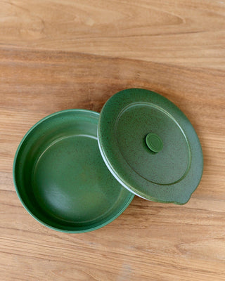 Green ceramic bowl with lid on a wooden surface