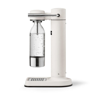 White carbonation machine with a clear bottle filled with carbonated water on a white background