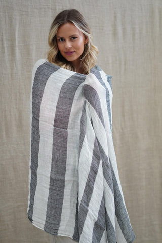Woman wearing a striped poncho against a neutral background