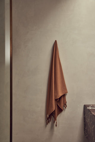 Brown towel hanging on a wall in a bathroom setting