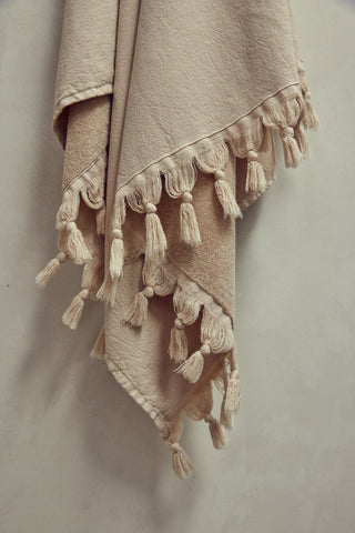 Beige blanket with tassels on a light gray background