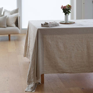 Beige tablecloth on a dining table with a vase of flowers in a bright room.