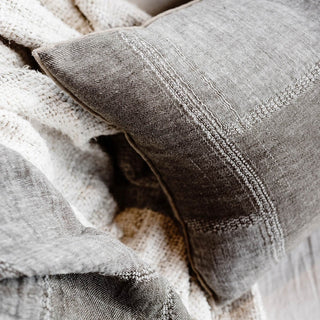 Textured gray pillow on a soft fabric surface