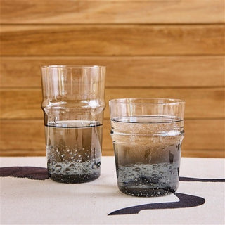 Two glass tumblers with water on a wooden surface
