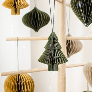 Decorative paper ornaments in green and brown hanging on a wooden rack.